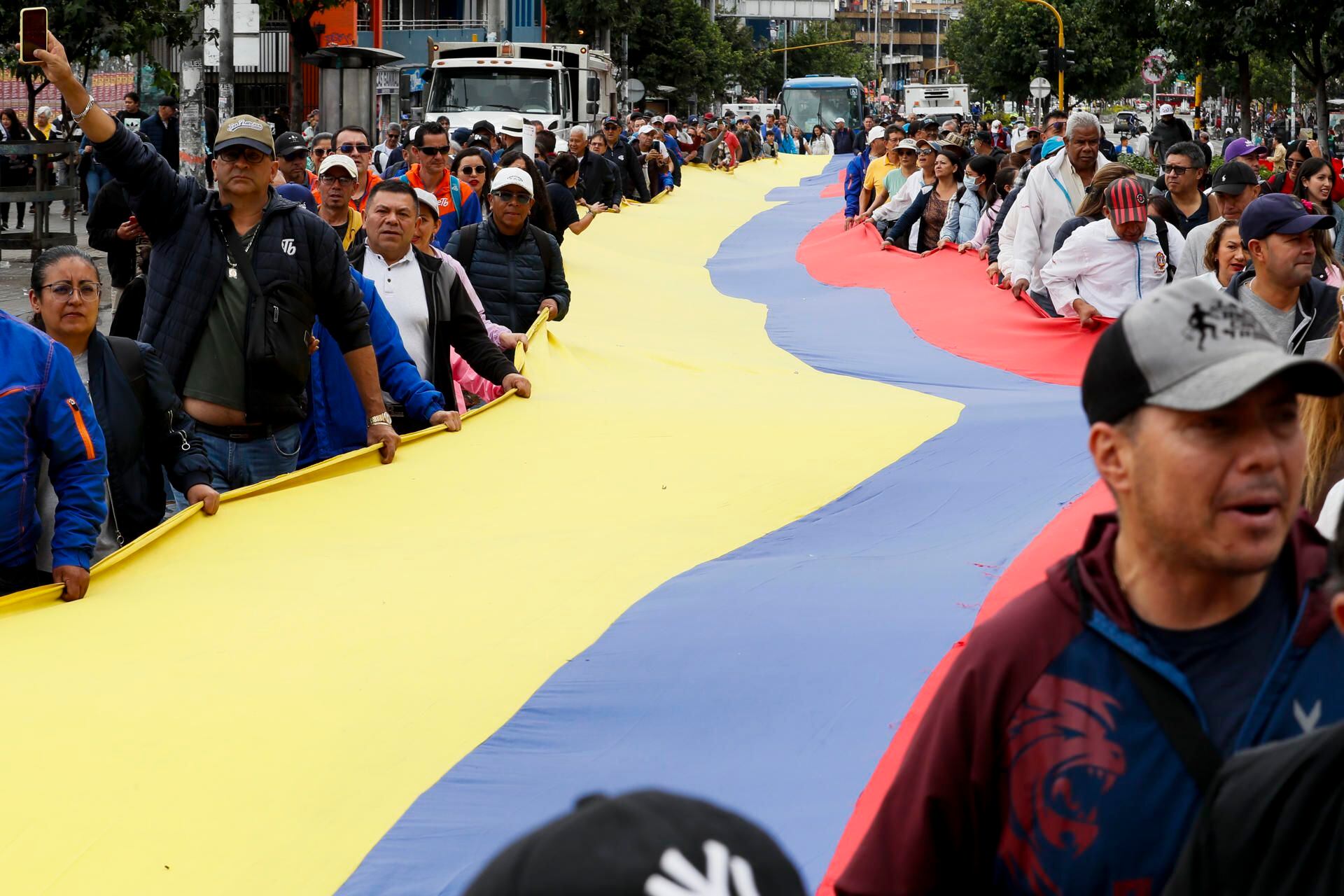 Varias personas sostienen una enorme bandera colombiana durante una marcha con motivo Día Internacional de los Trabajadores, en Bogotá (Colombia). EFE/ Carlos Ortega