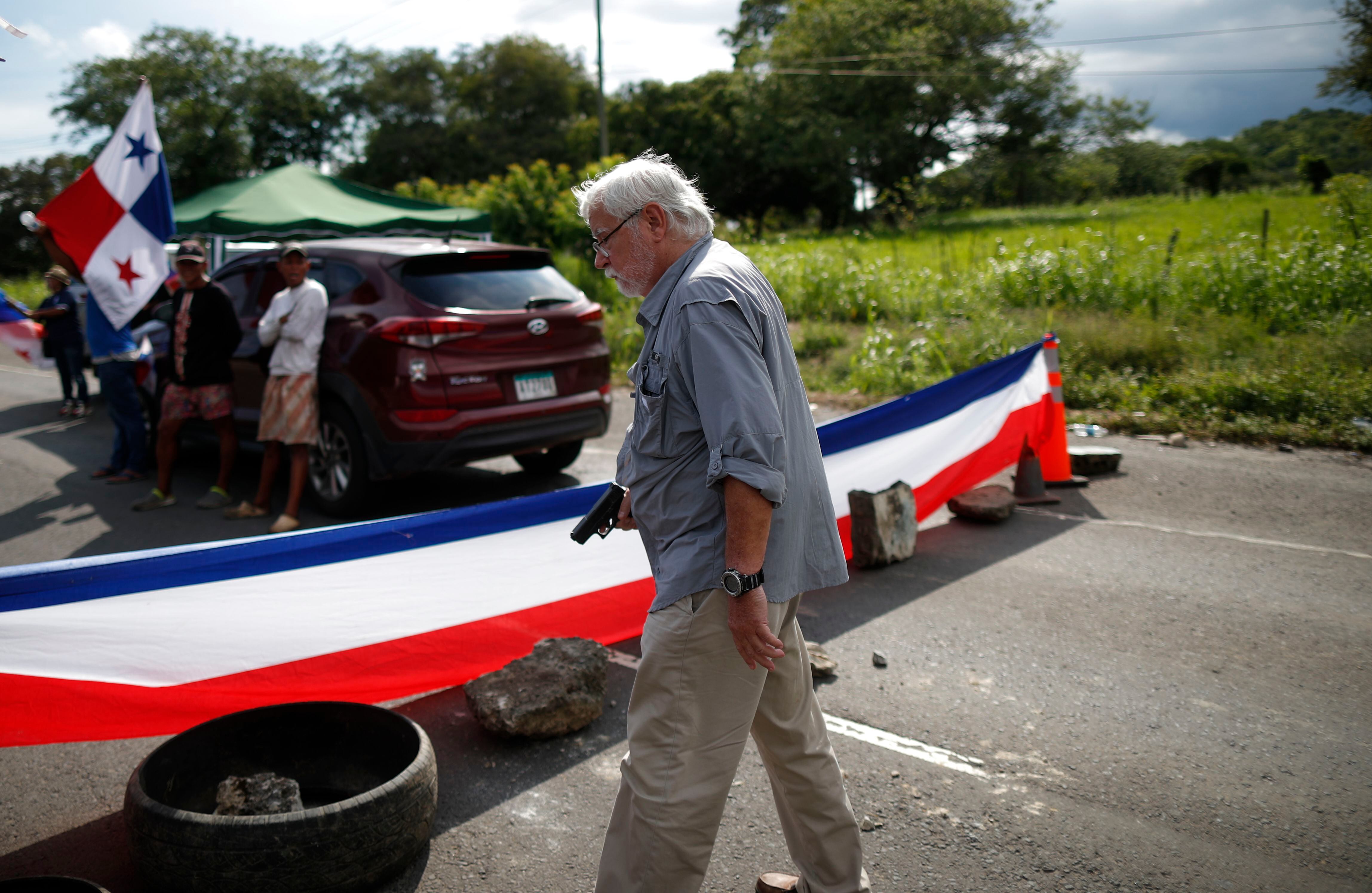 Un hombre sostiene un arma en medio de un bloqueo de docentes en la vía Panamericana en Chame. EFE/ Bienvenido Velasco
