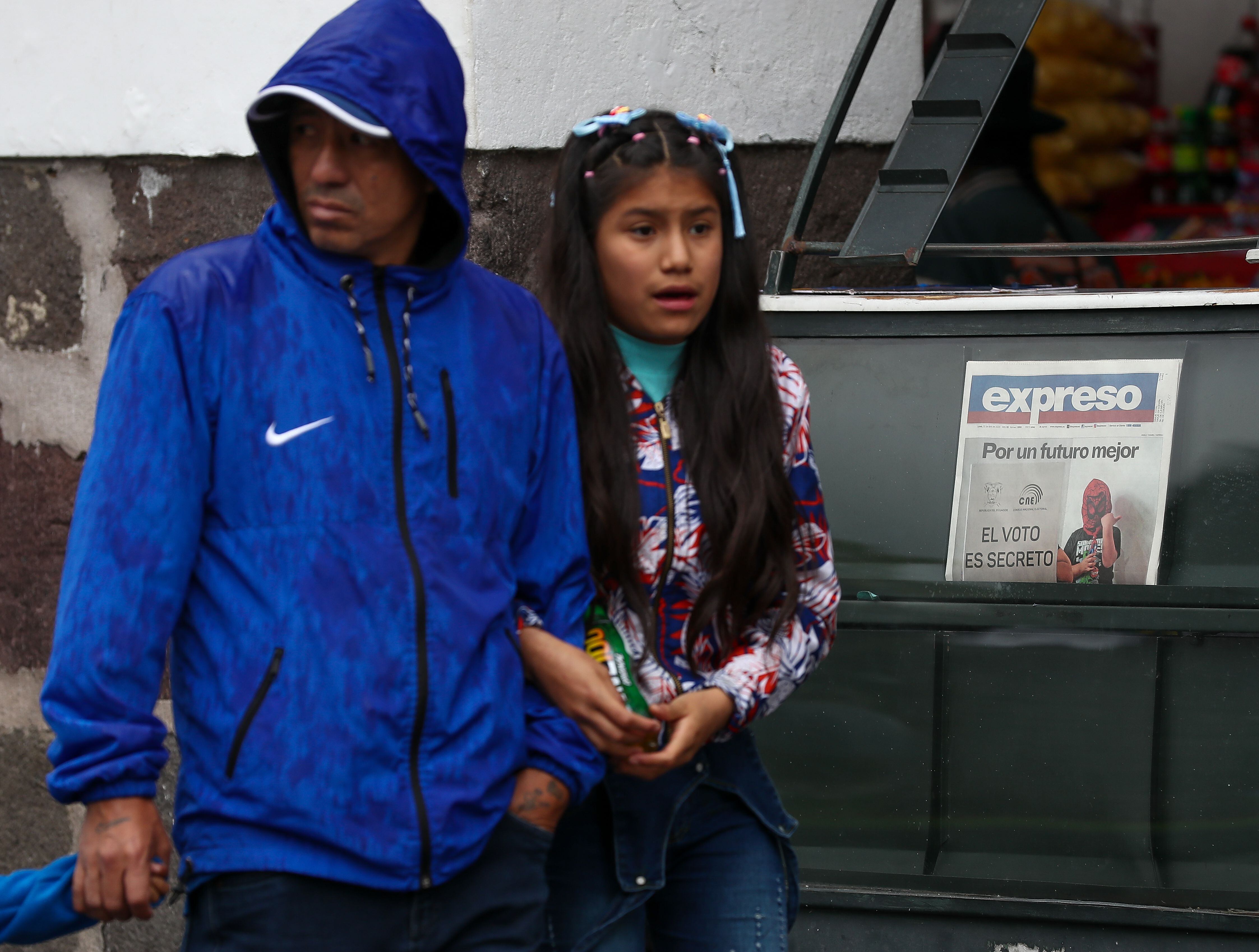 Transeúntes caminan frente a un puesto que exhibe un periódico informando sobre el referéndum del domingo, en Quito (Ecuador). EFE/ José Jácome
