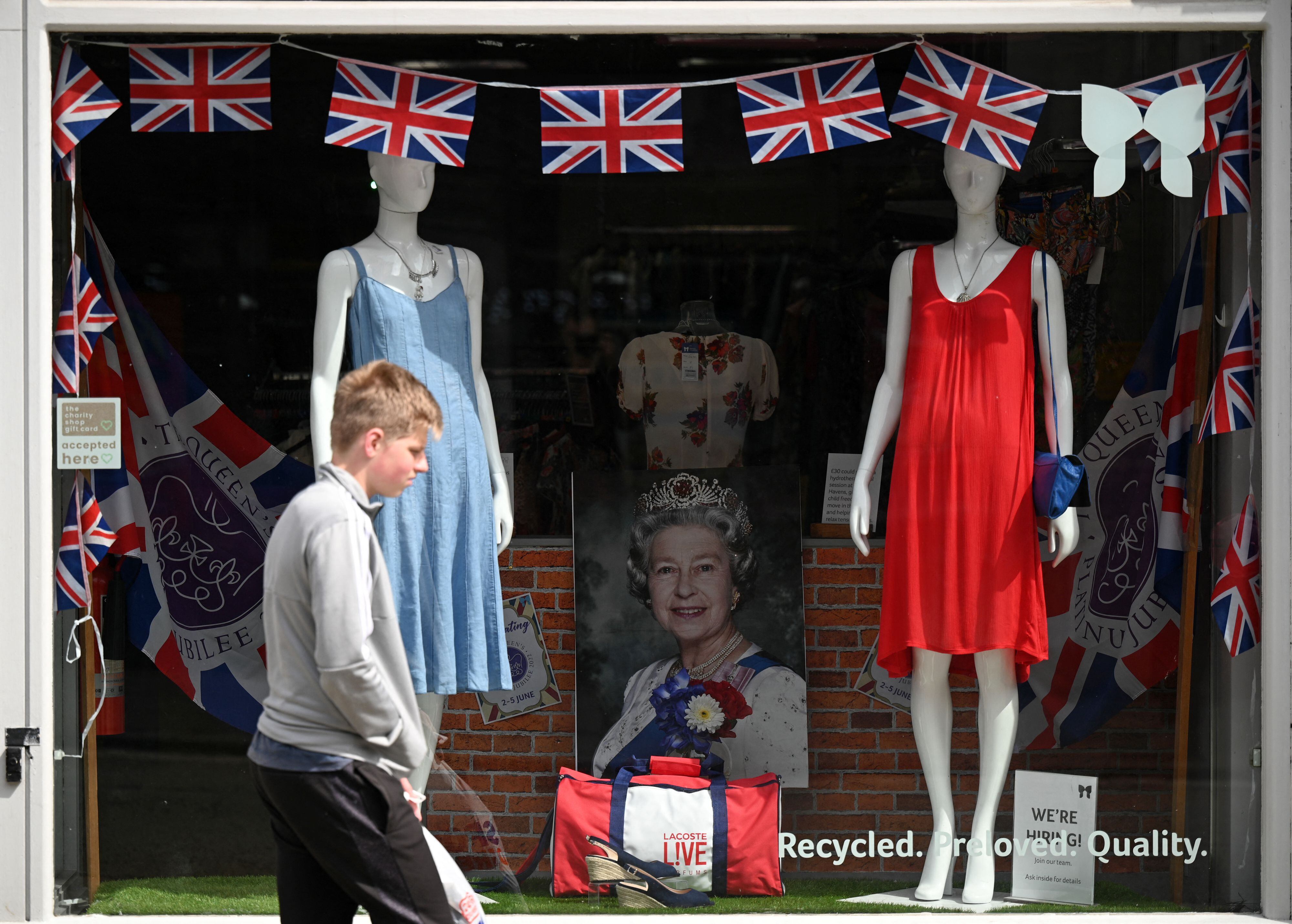 Un peatón pasa por un escaparate adornado con banderines y un retrato de la reina Isabel II, en Colchester. AFP/Daniel Leal