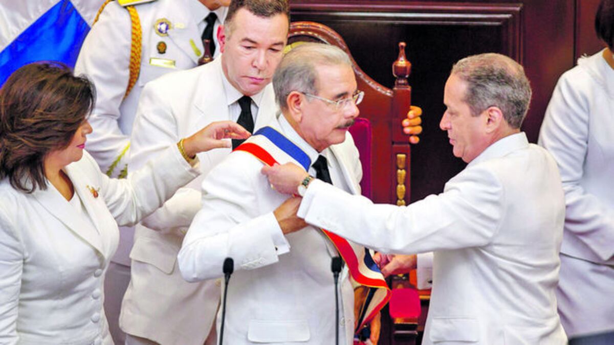 Momentos en que el presidente del Senado, Reynaldo Pared, impone a Danilo Medina la banda presidencial; a su izquierda, la vicepresidenta Margarita C. de Fernández.AFP