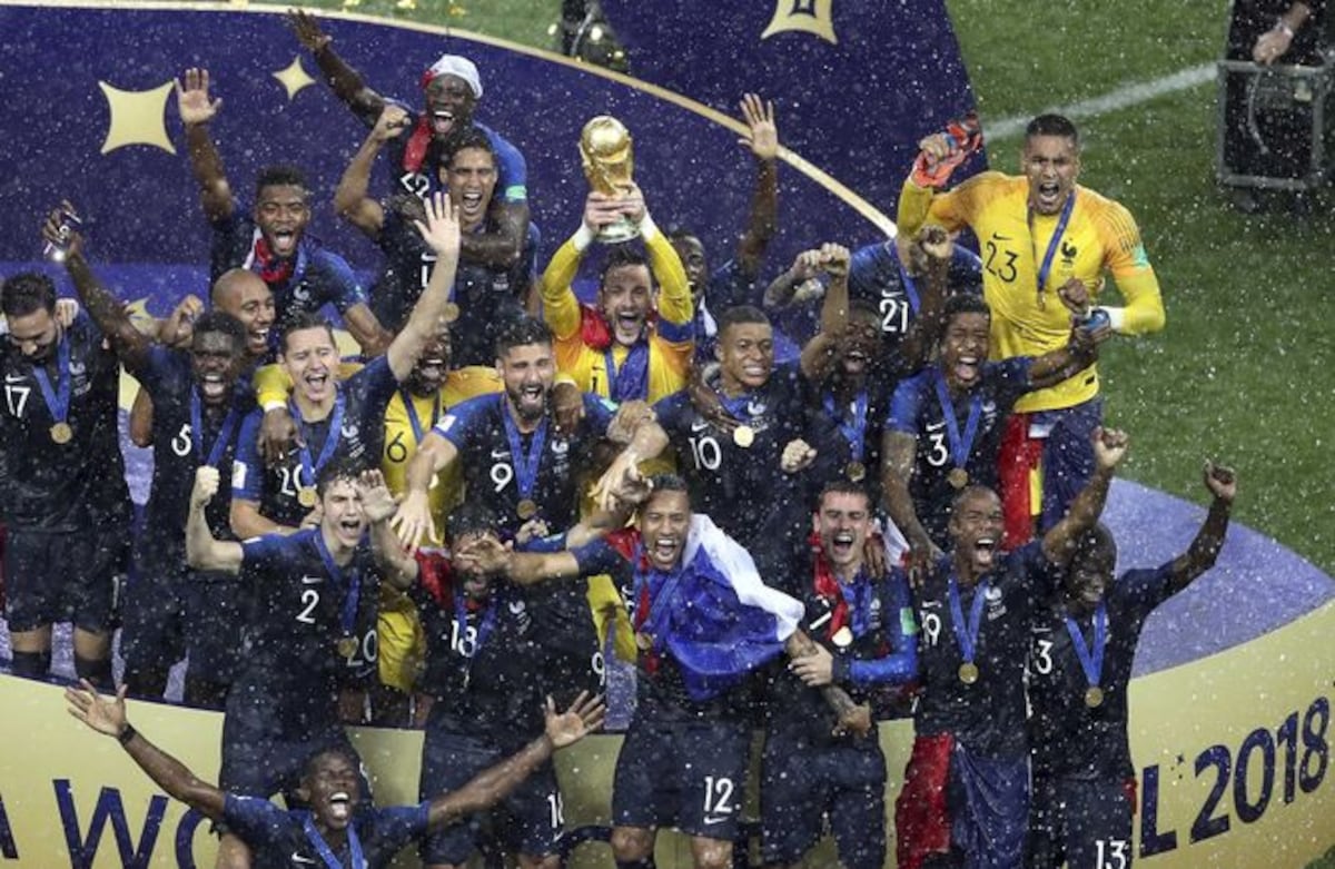 En medio de un fuerte aguacero los franceses levantan la copa del mundo.