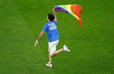 Un aficionado salta al césped con una bandera arcoíris en el partido entre Portugal y Uruguay