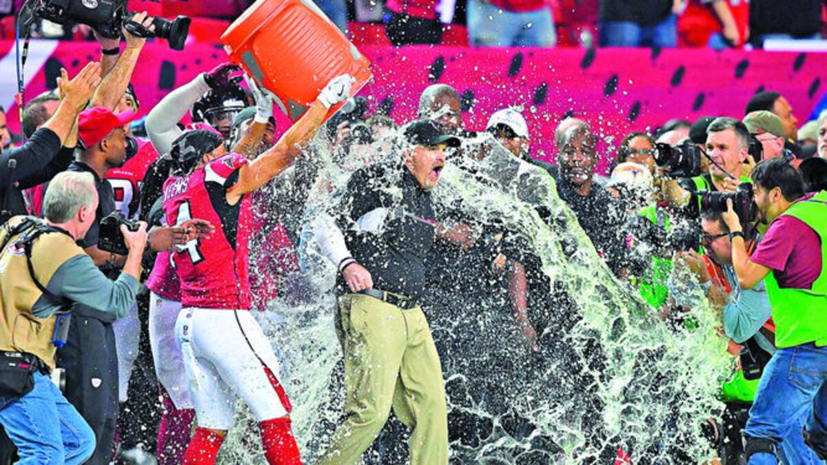 Eric Weems (14) encabeza un grupo de jugadores de Atlanta que le da el tradicional baño por el título al entrenador Dan Quinn, al final del partido.