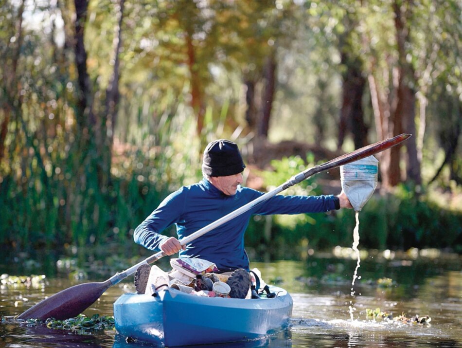 Mexicano recoge, con sus manos, la basura en canales de Xochimilco