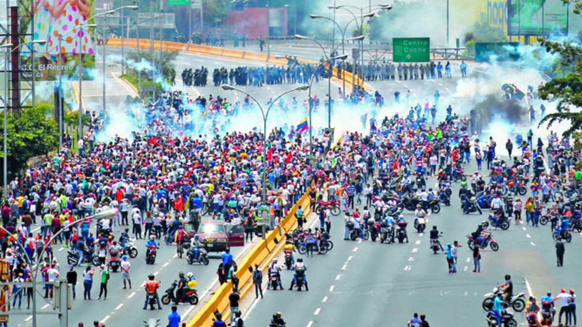 Cientos de ciudadanos avanzan por un sector céntrico de Caracas para desafiar a los cuerpos de seguridad que intentan impedirles el avance y dispersarlos con bombas lacrimógenas.