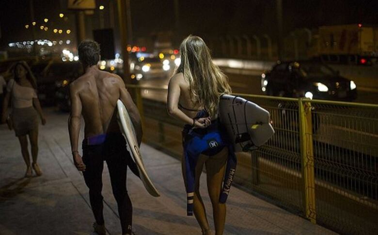 Surfistas nocturnos corren olas en playa de Lima