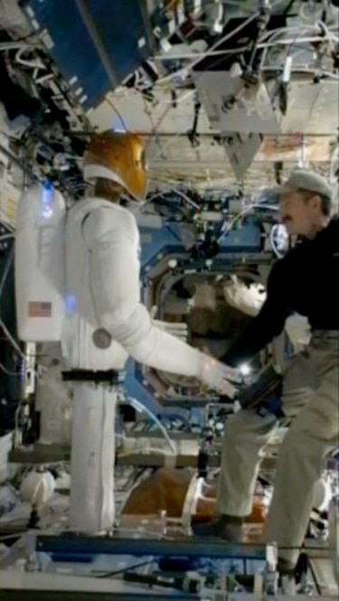 Humano y robot humanoide se saludan de mano en estación espacial