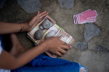 Billetes en desuso son el juguete de los niños en un pueblo de Venezuela