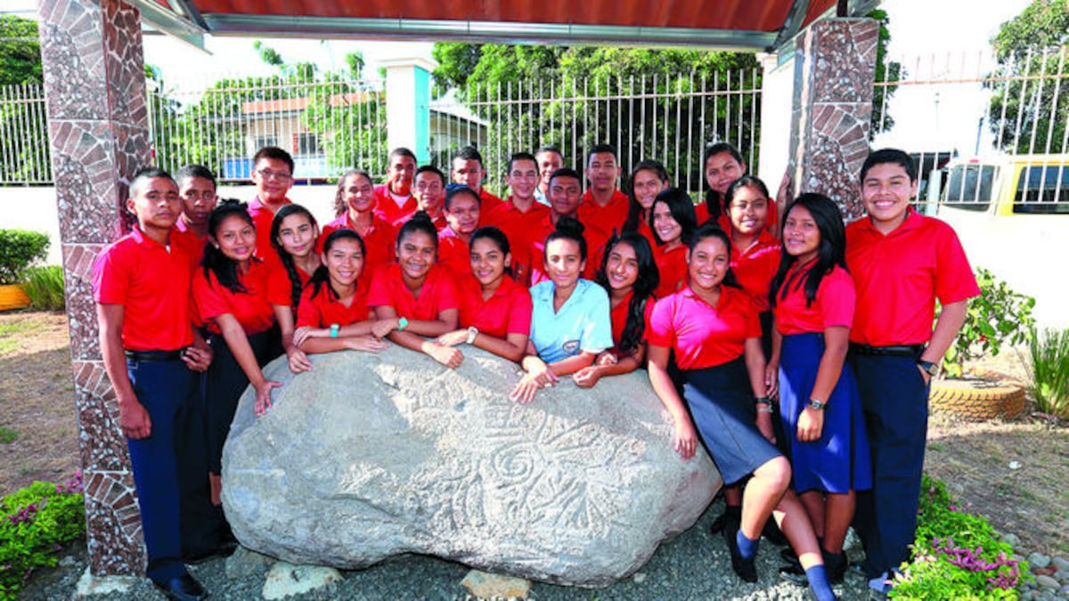 Estudiantes que forman parte del grupo Identidad junto al petroglifo que custodian en su centro educativo.