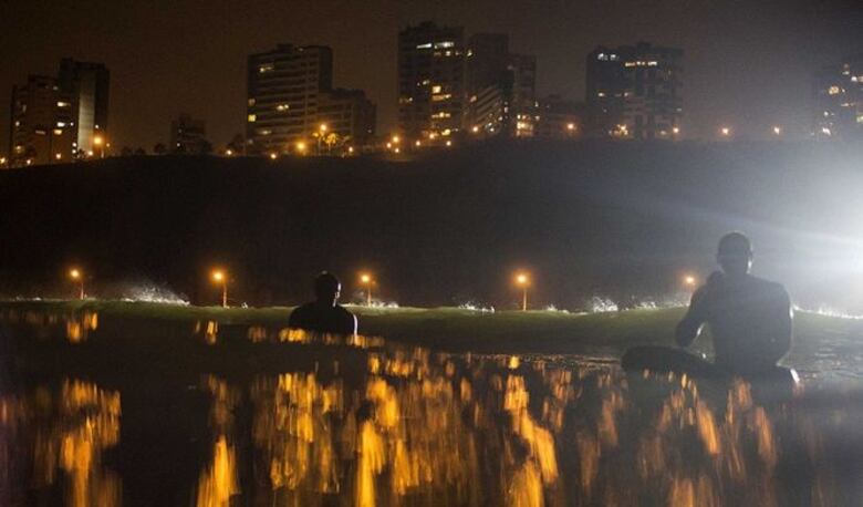 Surfistas nocturnos corren olas en playa de Lima
