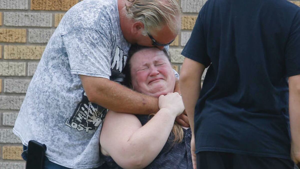 Un hombre abraza a una mujer fuera del gimnasio Alamo donde los padres esperan para reunirse con sus hijos des