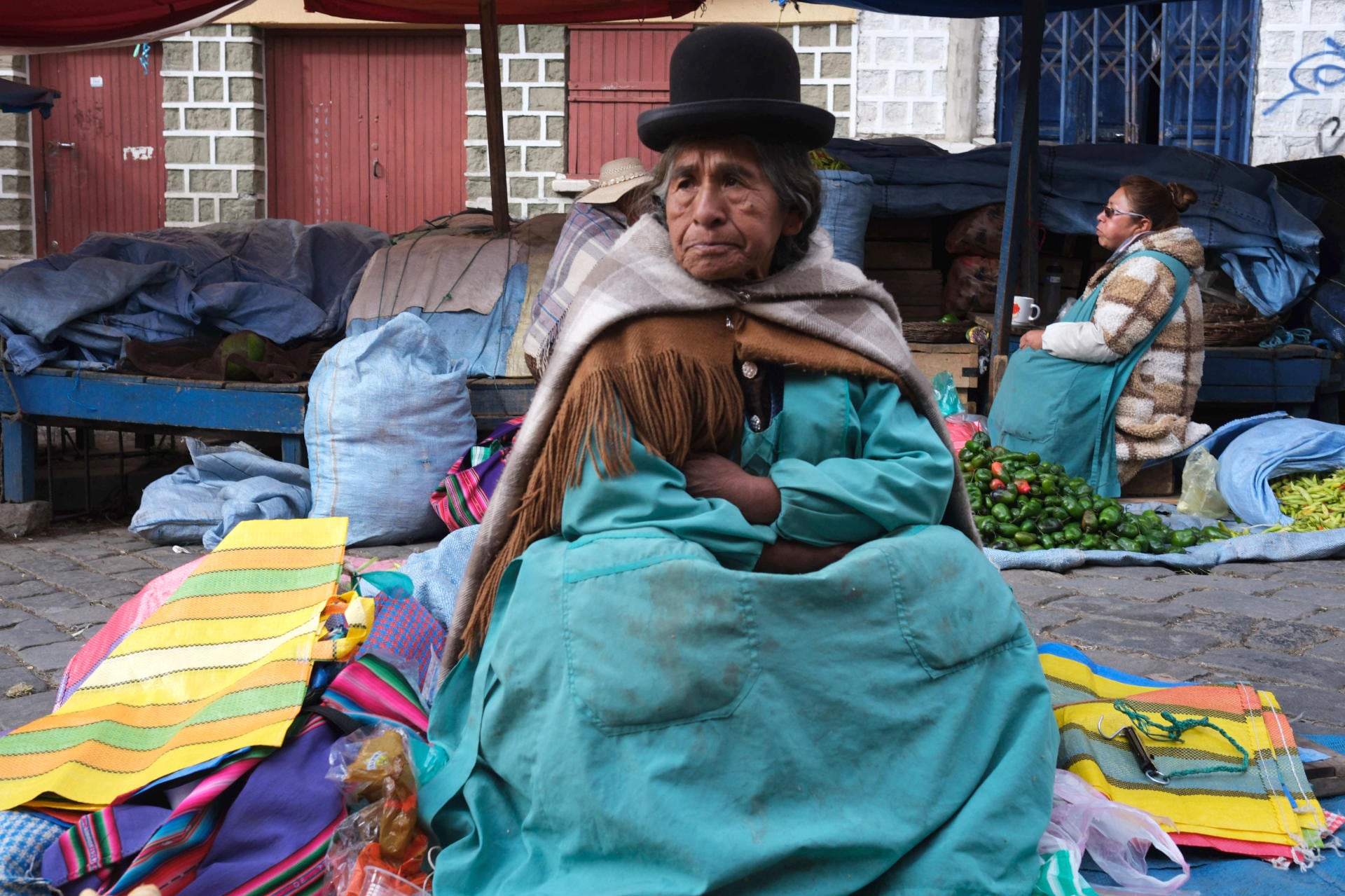 Una mujer aimara vende productos en un mercado popular este miércoles, en La Paz (Bolivia). El conflicto en Bolivia impulsado por sectores que exigen la renuncia del presidente Rodrigo Paz comienza a derivar en una emergencia humanitaria, tras la muerte de pacientes que no pudieron recibir atención médica y las crecientes dificultades para transportar oxígeno, medicinas y alimentos por los bloqueos de carreteras. EFE/Luis Gandarillas
